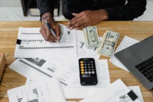 Espace de travail comptable avec ordinateur portable, calculatrice et documents financiers pour préparer une facture proforma