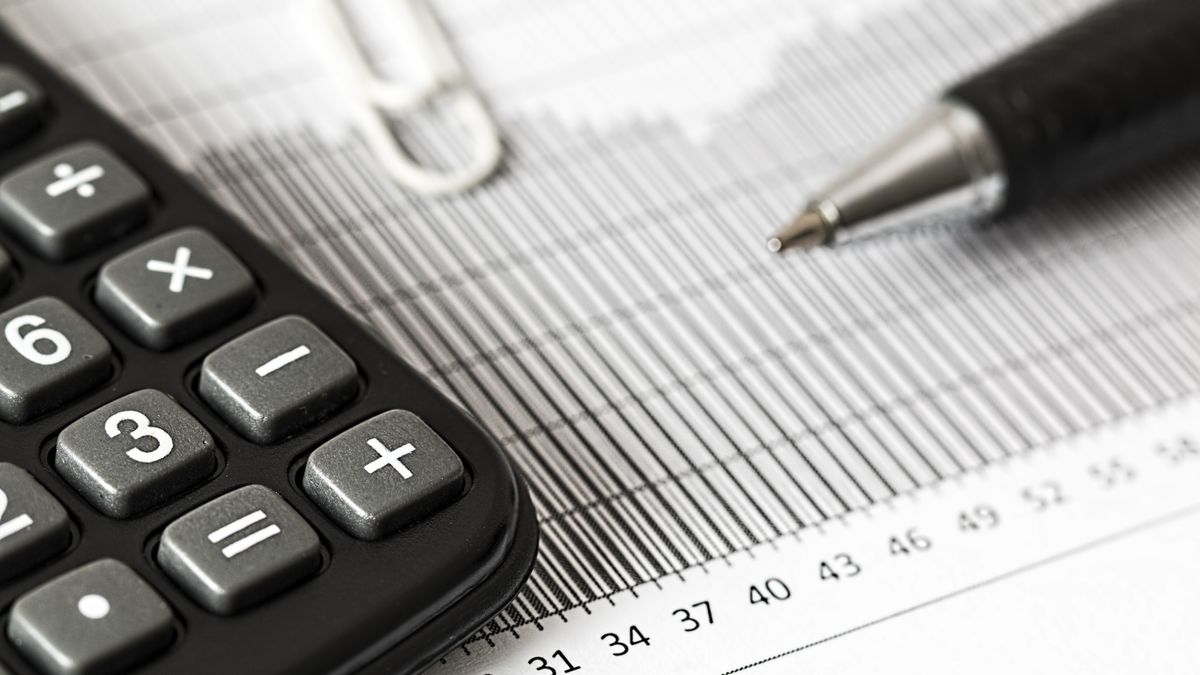 Calculatrice et stylo sur un bureau, symbole du calcul de la paie et de la comptabilité